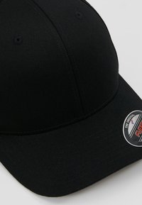 Zwarte baseballpet met een gebogen klep, gemaakt van textuurstof. Heeft een ronde label met branding aan de zijkant. Eenvoudig ontwerp, geen patronen.