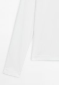 White long-sleeve shirt sleeve and hem, shown against a white background with visible fabric texture and stitching details.