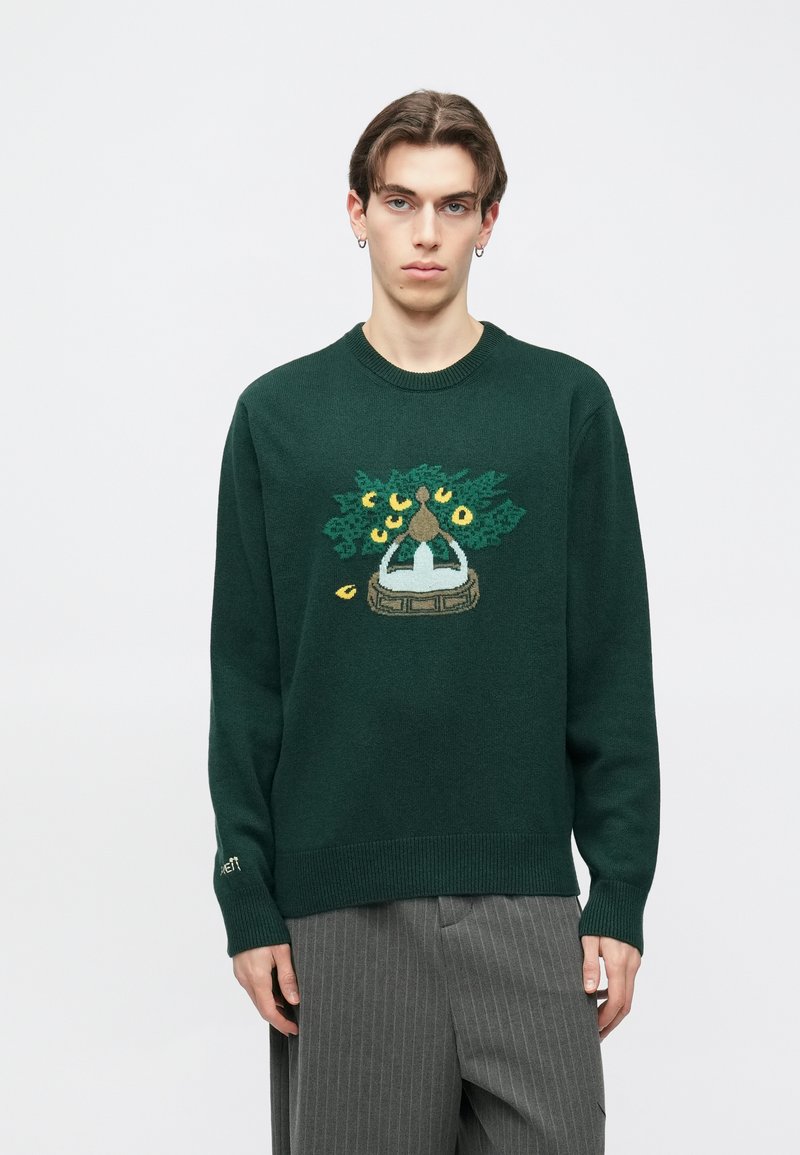 Zaļš adīts džemperis ar krāsainu gobelēna dizainu priekšpusē, ar ribotām aprocēm un apakšmalu, kas piešķir tekstūru un pieguļošu siluetu.