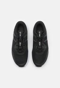 Scarpe sportive nere con tomaia in rete, caratterizzate da un design testurizzato, chiusura con lacci e suola bianca. Accentuate con il marchio "Just Do It".