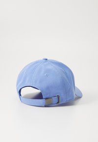 Căciulă de baseball albastră cu coama curbată, curea ajustabilă la spate și un accent metalic cu logo. Fabricată dintr-un material texturat.