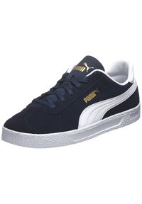 Zapatilla de ante azul marino con acentos blancos, suela de goma texturizada, detalles en negro y logotipo dorado de la marca en el lado lateral.