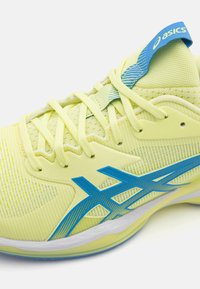 ASICS sportsko i lys gul med blå detaljer, teksturert mesh-overdel, fremtredende snøring og en polstret såledesign.