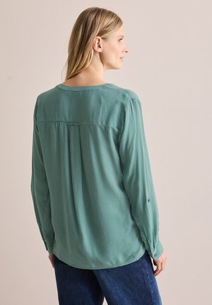 Lichtgroene gestreepte blouse met lange mouwen, knoopmanchetten en een ronde zoom. De achterkant heeft een yoke-naad en een losse pasvorm.