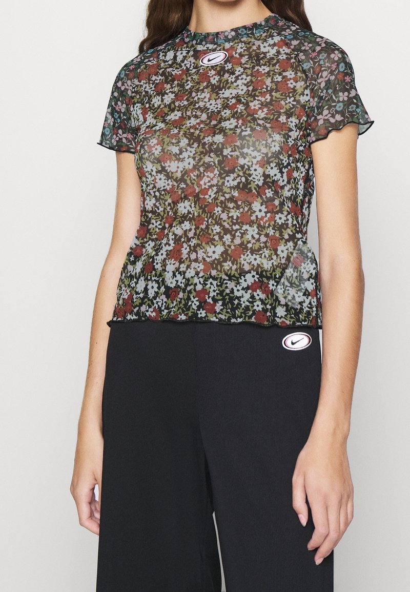 Průhledné květinové tričko s kulatým výstřihem a krátkými rukávy, s mnohobarevným květinovým vzorem na černém pozadí a nášivkou s logem Nike.