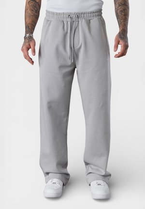 Light gray sweatpants made of soft fabric, featuring an elastic waistband with drawstrings, side pockets, and a loose fit.
