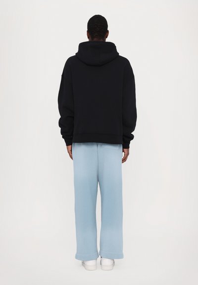 Black hooded sweatshirt and light blue wide-leg pants, made of soft fabric. The pants feature a simple design with a relaxed fit.