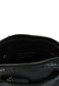 Zwarte leren tasinterieur met ritsluiting, voorzien van een zachte textuur, een hoofdcompartiment en een extra kleinere ritszak.