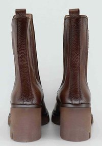 Stivali ankle in pelle marrone con finitura testurizzata, tacco a blocco e pannelli elastici sui lati. Presentano un discreto tassello sul retro.