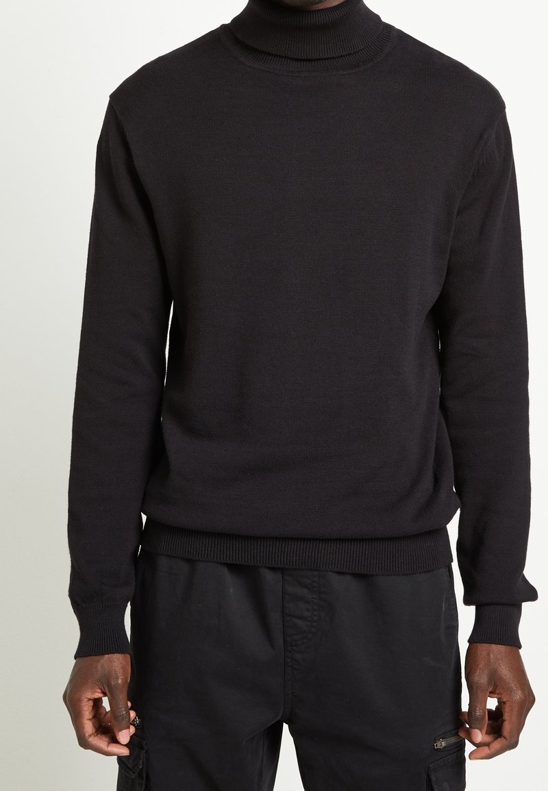 Black turtleneck sweater made of knit fabric. Features long sleeves and a fitted silhouette with ribbed cuffs and hem.