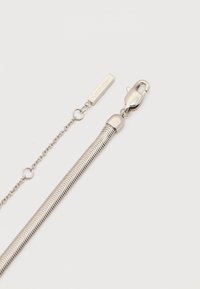 Collier Calvin Klein en argent avec fermoir pince de homard et chaîne réglable sur fond blanc.