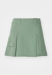 Grønn bomullsskjørt med plissert design, som har en sidelomme og kontrastsøm. Ingen ekstra pynt eller mønstre.
