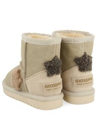 Bottines en daim tan avec des accents d'étoiles duveteux et une doublure intérieure beige. Présente une semelle texturée et une étiquette de marque.