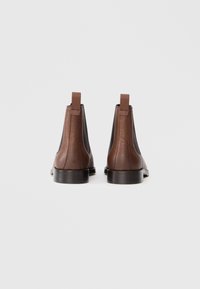 Bottes Chelsea en cuir marron avec un dessus texturé, des panneaux latéraux élastiques et des languettes ; semelle en caoutchouc ; design minimaliste.