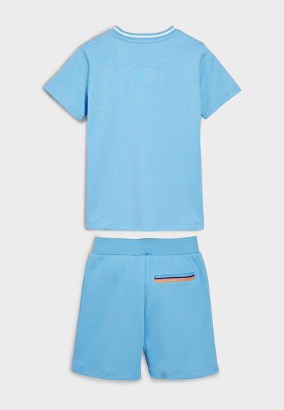 Svetlomodré tričko s krátkymi rukávmi a zodpovedajúce šortky, ktoré majú pruhovaný pás a dekoratívny vreckový detail s multikolórovými pruhmi.