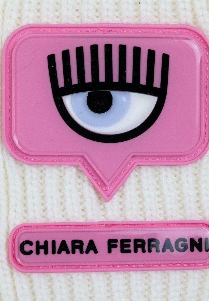 Weißer Strickstoff mit einem pinkfarbenen Gummipatch, der ein Augendesign mit Wimpern zeigt, und einem Namensschild mit der Aufschrift "CHIARA FERRAGNI" darunter.