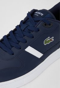Marineblaue Ledersneaker mit weißen Akzenten, runden Schnürsenkeln, einem kleinen gestickten Krokodil-Logo und einer strukturierten Gummisohle.
