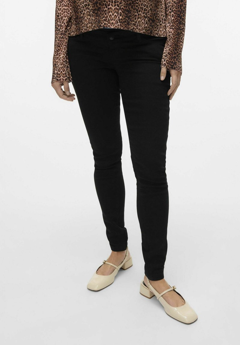 Jeans negros ajustados con una textura suave, combinados con zapatos de tacón cuadrado beige que tienen una tira en el pie. Elegante blusa de print leopardo.