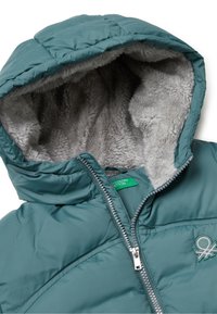 Turkusowa puchowa kurtka z szaro-futrzanym kapturem, zamek błyskawiczny z przodu i wyszywanym logo na piersi. Teksturowany, ocieplany materiał.