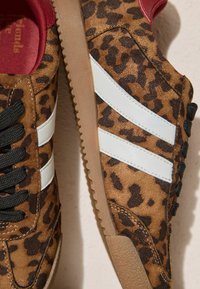 Mockasinners med leopardmönster, vita ränder, svarta snören och röda detaljer. Har en texturerad gummisula och vadderad kant.