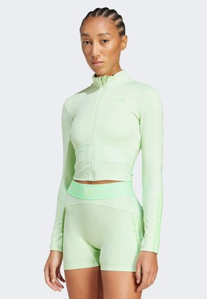 Lichtgroene sportset met een ritsloze lange mouw top en hoge taille korte broek met ribbeltextuur en drie strepen op de mouwen.