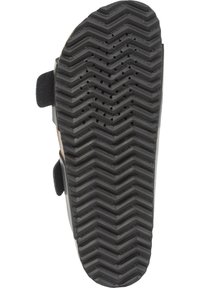 Suola di scarpa nera in gomma con un motivo a zigzag, texturizzata per la presa, con perforazioni sulla superficie e attacchi con strap in velcro.