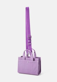 Purple canvas tote bag with adjustable shoulder strap and dual top handles, featuring silver hardware and stitched accents on the sides.