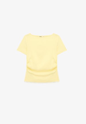Haut femme jaune clair à manches courtes avec encolure ronde, côtés froncés et délicate bordure en dentelle blanche à l'ourlet.