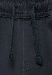 Čierne jogger nohavice z látky s elastickým pásom a šnúrkou. Obsahujú viditeľné švy a diskrétny detail bočnej vrecka.