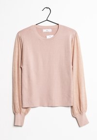 Maglione lungo rosa chiaro a maniche lunghe con texture di maglia miste, scollatura rotonda e polsini a costine, sospeso su una gruccia nera su uno sfondo bianco.