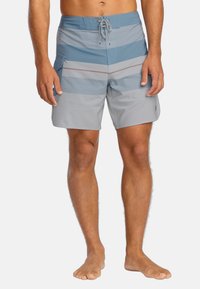 Šedé a modré pruhované plavky s nastaviteľným pásom na šnúrku, bočnou kapsou a hladkou, ľahkou textúrou látky.