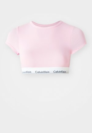Pink cropped t-shirt with short sleeves, made of smooth fabric. Features a white band with "Calvin Klein" logo at the bottom.