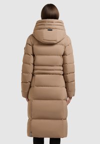 Hosszú, bélelt kabát világosbarna színben, kapucnival, vízszintes rudakkal és oldalsó cipzáras zsebekkel. Simább, szintetikus anyag, laza fazonnal.