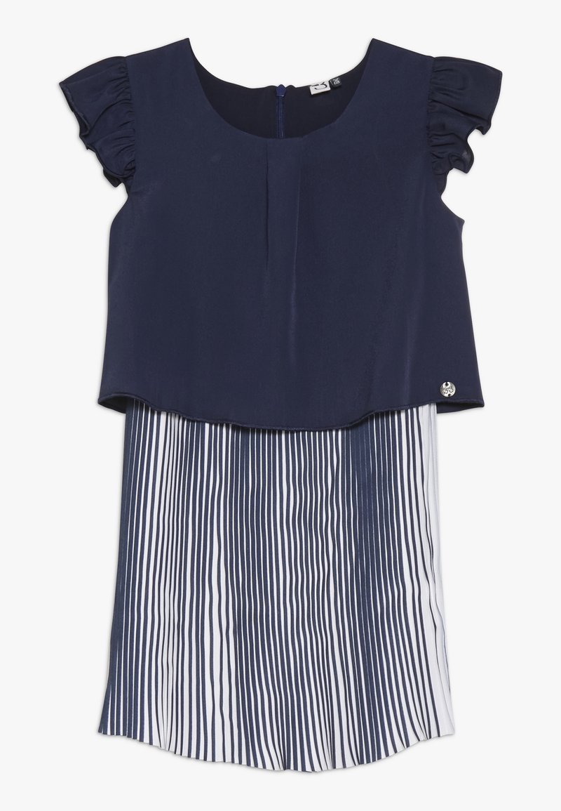 Námořnická modrá blůza s volnými rukávy pokrývá bílou sukni s vertikálními námořnickými pruhy. Hladká textura s kulatým výstřihem.