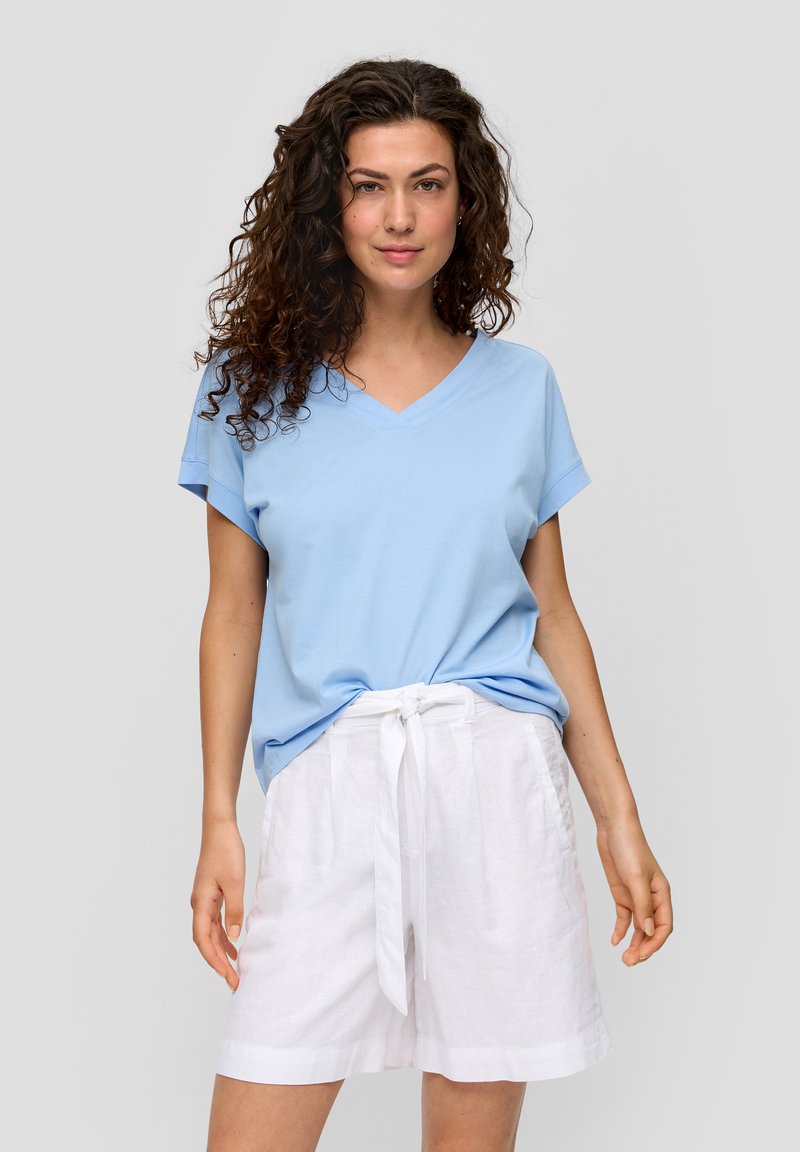 Lichtblauwe katoenen t-shirt met een V-hals en korte mouwen, gecombineerd met witte linnen shorts met een trekkoord in de taille.