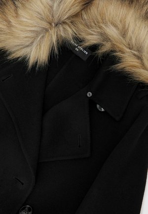 Černý vlněný kabát s límcem z umělé kožešiny, šitými reverzy a knoflíkovým zapínáním. Hladká textura s minimálními viditelnými švy.