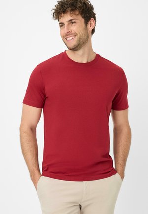 Rød, kortærmet bomulds t-shirt med rund hals. Har en blød tekstur og en tætsiddende design, parret med beige bukser.