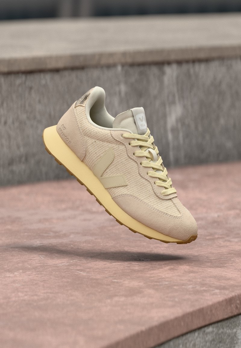 Baskets beiges avec une tige en maille, semelle en caoutchouc et détails texturés. Dotées d'un col rembourré et d'un logo sur la languette. Design léger.