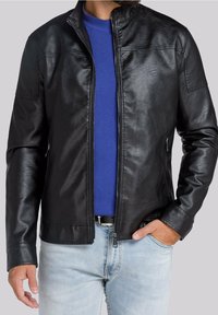 Giacca in pelle nera con colletto alzato, caratterizzata da una cerniera frontale, due tasche laterali e una texture liscia, indossata sopra un maglione blu.