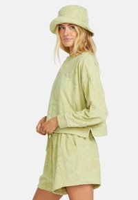 Lys grøn terrycloth sweatshirt og shorts sett med et preget bladmønster. Kombinert med en matchende bøttehatt.