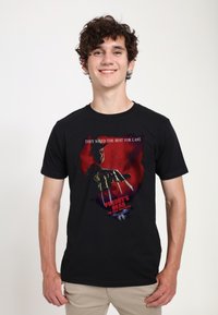 Czarny bawełniany t-shirt z nadrukiem graficznym przedstawiającym postać z horroru z rękawiczką na dłoni i czerwonym tłem; napis głosi "Freddy's Dead."