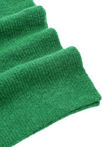 Zielona, teksturowana tkanina z pionowymi prążkami, prezentująca miękką, puszystą powierzchnię. Tkanina jest złożona, co podkreśla głębię i bogactwo koloru.