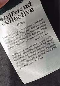 Kleidungslabel mit dem Markennamen "girlfriend collective", hergestellt in Vietnam, 100% recyceltes Polyester, Text in mehreren Sprachen.