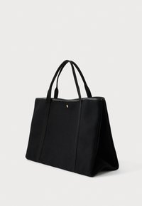 Μαύρη ορθογώνια τσάντα tote με διπλούς χειρολαβές, μαλακό ύφασμα σώματος και λευκές ραφές κατά μήκος της επάνω άκρης, που στέκεται σε άσπρο φόντο.