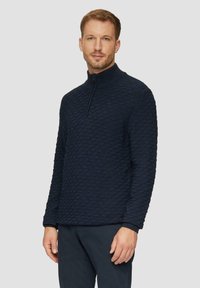 Dunkelblau gestrickter Pullover mit einem Rautenmuster, hohem Kragen und halblangem Reißverschluss. Lange Ärmel und strukturierter Stoff.
