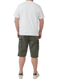 Biała bawełniana koszulka z okrągłym dekoltem, zestawiona z oliwkowymi szortami cargo z bocznymi kieszeniami oraz beżowymi trampkami z granatowymi akcentami.