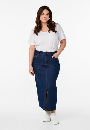 Falda maxi de mezclilla en azul oscuro con una abertura en el frente, combinada con una camiseta blanca de corte en V y zapatillas blancas. Cuenta con un bolsillo en la cintura.