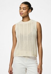 Ärmlös krämfärgad stickad topp med ett mönster av vertikala ränder och öppen väv. Urringningen är ribbad med en avslappnad passform.