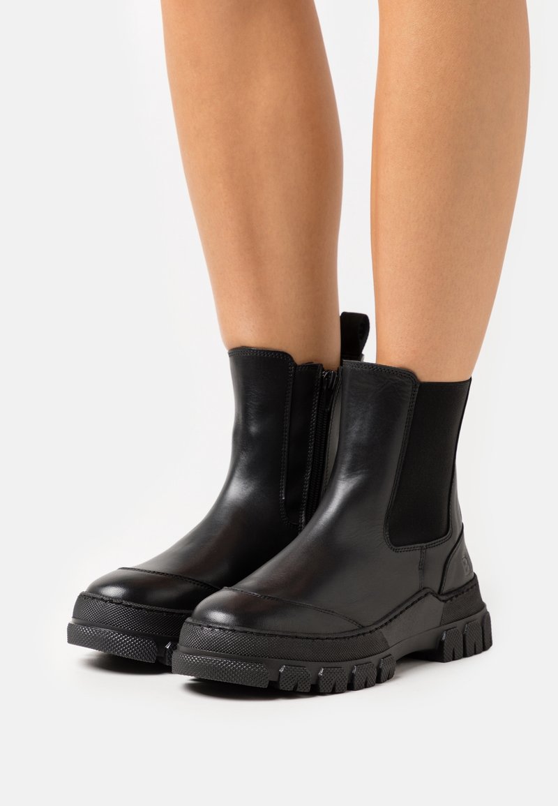 Mustat nahkaavokkaat nilkkoihin, joissa on joustavat sivupaneelit, sivuvetoketju ja kestävä kumipohja, jossa on karkea kuviointi.