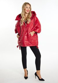 Rød puffy jakke med hætte, quiltet mønster, lynlås lukning og sidebånd. Sammen med sorte leggings og højhælede sko.
